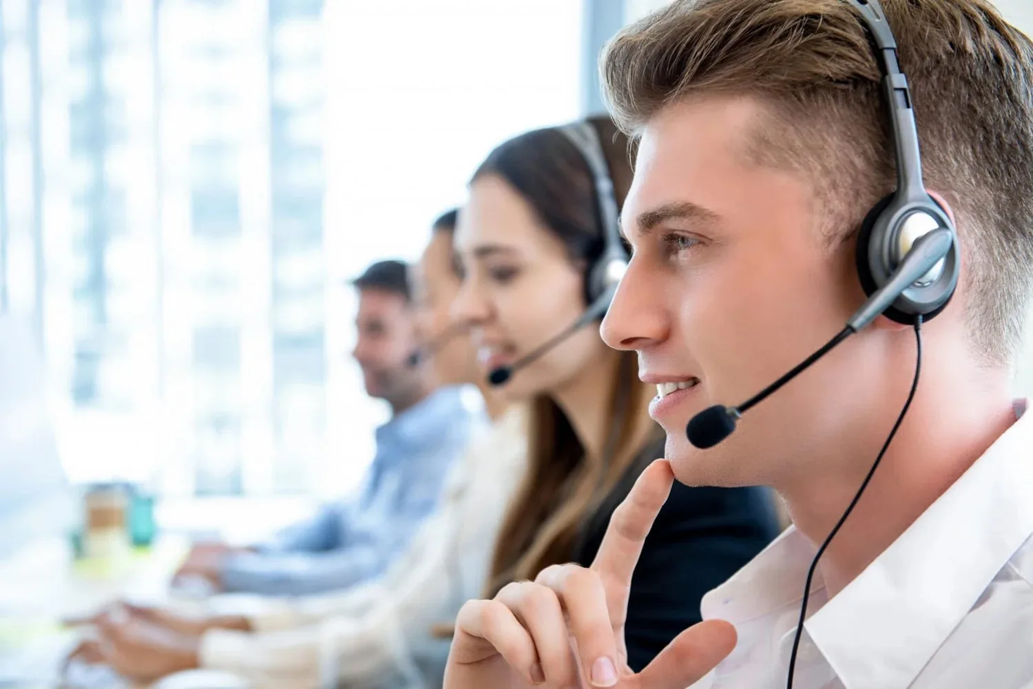 Smiling contact-centre agents on headsets helping customers